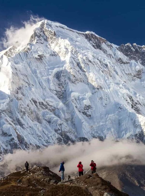 everest three passes trek with trekkers on a rocky ridge and panoramic snow-covered himalayan mountains under a clear blue sky